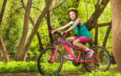 Smiling young girl cycling through spring woodland